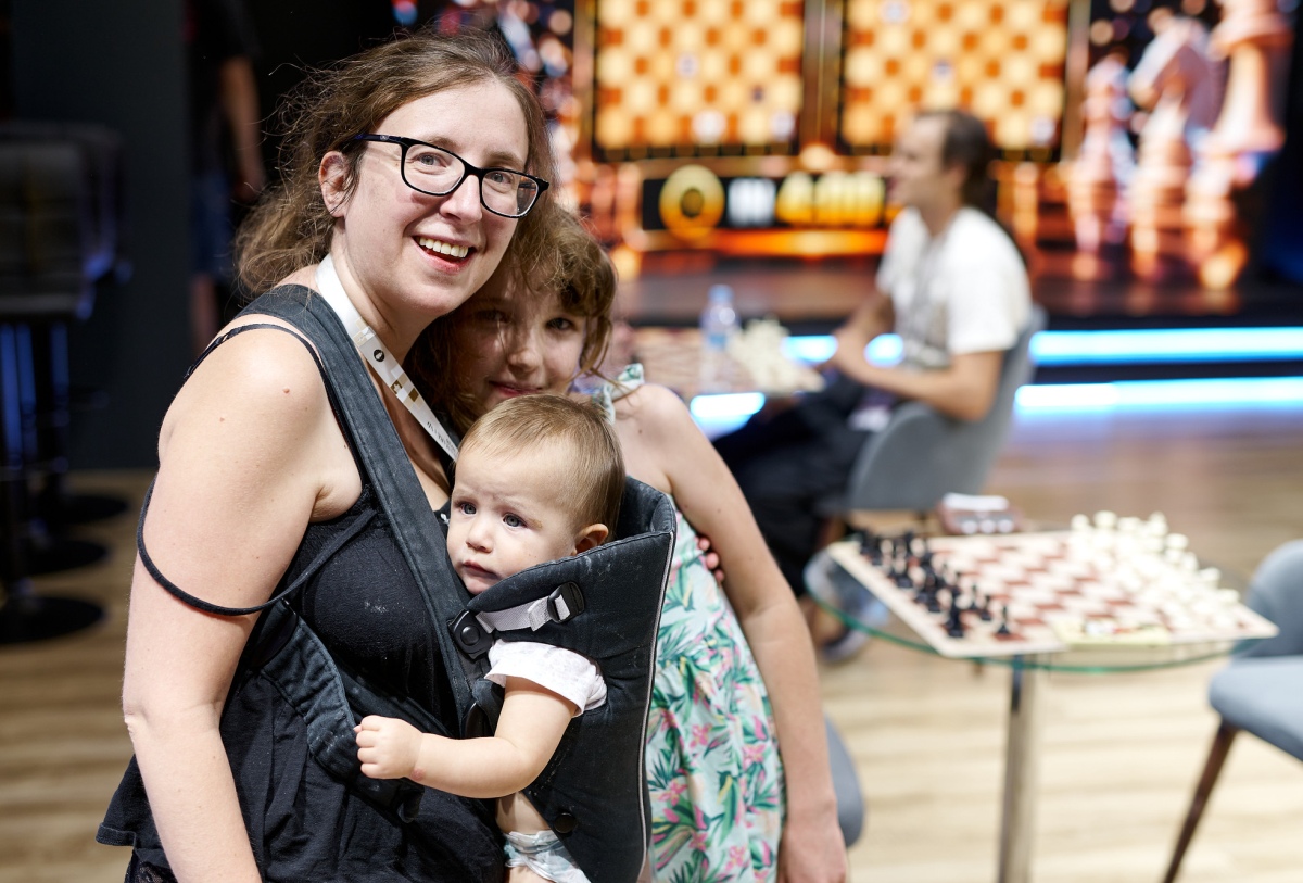 一位棋手在国际象棋场地抱着婴儿。