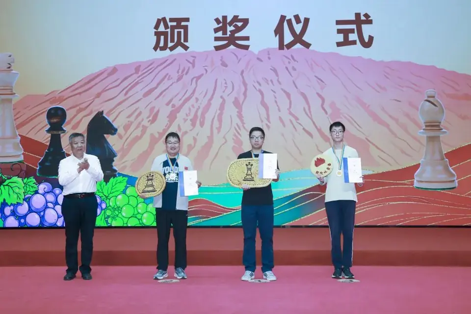 吐鲁番棋协大师赛公开组前三名在颁奖台上领奖。